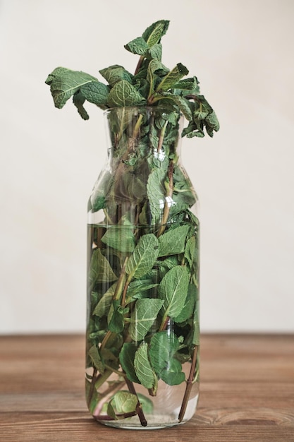 Closeup of mint leaves in vase with water placed on wooden table refreshing ingredient for dishes