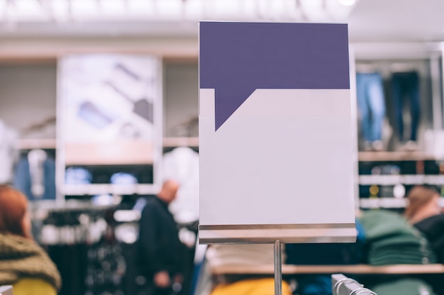 Photo closeup, mock up of a white signboard on the background of a store with clothes.