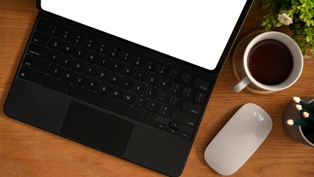 Closeup Mockup blank screen of a tablet computer with keyboard and stuff on wooden table