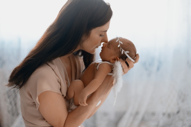 写真 クローズアップママは彼女の生まれたばかりの天使に優しくキスしています