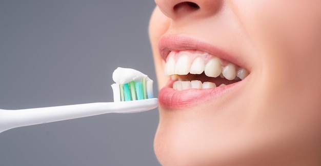 Closeup mond met tandenborstel Tandheelkundige gezondheidszorg kliniek Close-up van een jonge vrouw poetst haar tanden Tandenborstel met tandpasta Tandheelkundige banner copyspace
