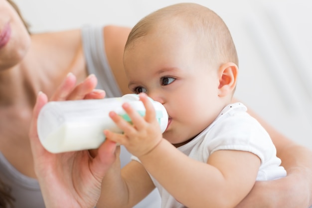 Closeup of mother feeding baby with milk bottle