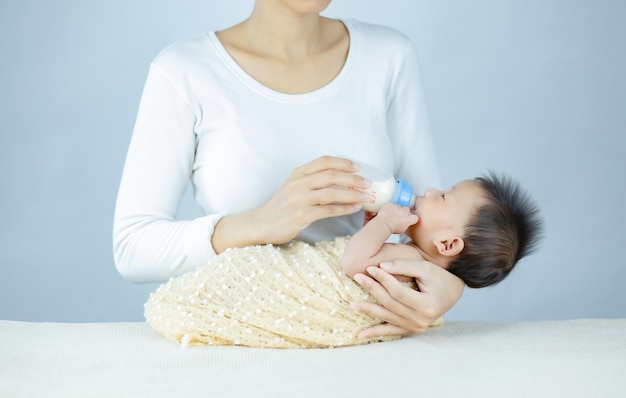 Closeup mother feeding infant baby by bottle
