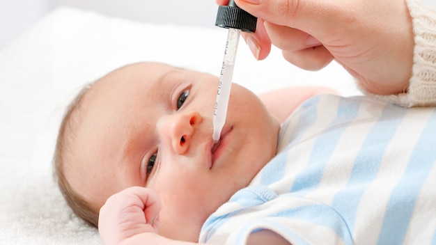 Closeup of mother giving vitamin D and K to her newborn baby from eyedropper