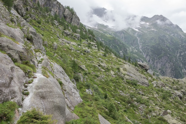 Closeup mountains scenes, walk to Trift Bridge in national park Switzerland, Europe. Summer landscape, sunshine weather, dramatic cloudy sky and sunny day