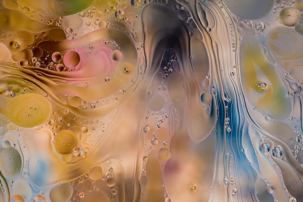 Closeup of the movement of oil droplets on the water surface\
colorful abstract macro background of oil drops on the water\
surface