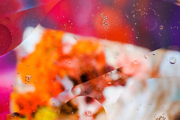 Closeup of the movement of oil droplets on the water surface\
colorful abstract macro background of oil drops on the water\
surface