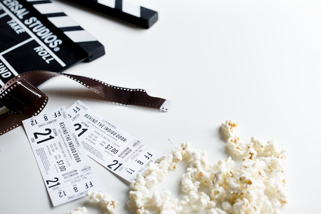 Photo closeup of movie tickets with popcorn and reels decoration on white table