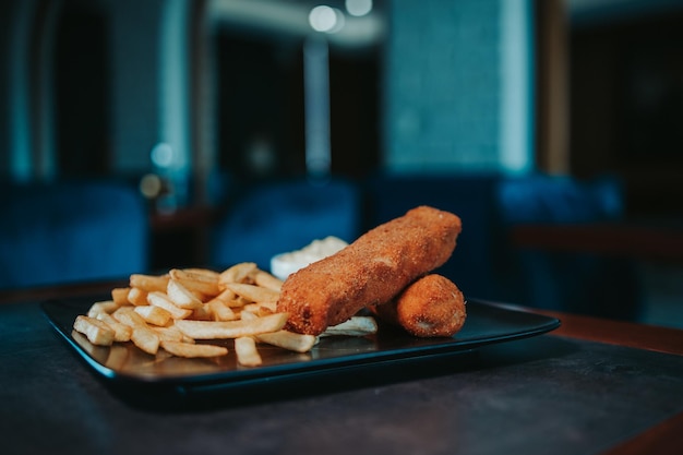 Closeup of mozzarella sticks with french fries and a white side sauce on a plate on the table
