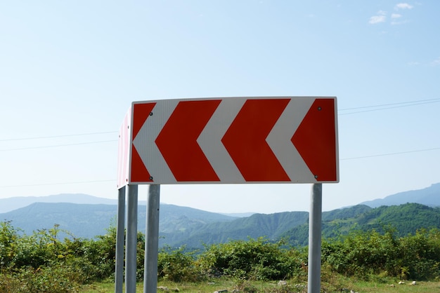 Крупный план многооборотного дорожного знака на извилистой горной дороге