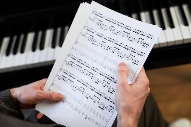 Closeup of musician holding the sheet music and examining them before playing the piano