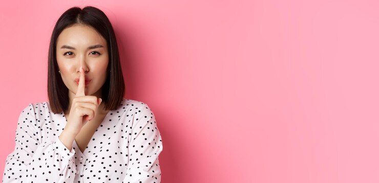 Photo 神秘的なアジアの女性のクローズアップは、秘密の静けさを隠し、円周率の上に立って静かにするように言います