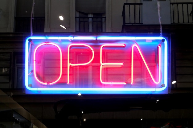 Closeup on a neon light shaped into a blue rectangle and the word open in red