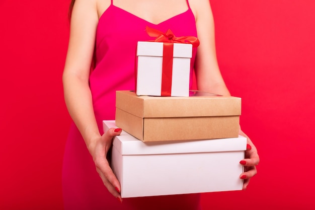 Closeup of new year's gifts in the hands of a woman on a red background