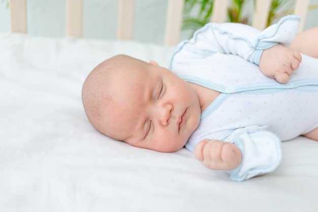 Крупный план новорожденного мальчика, спящего в кроватке дома в течение семи дней на хлопчатобумажной кровати здоровый детский сон