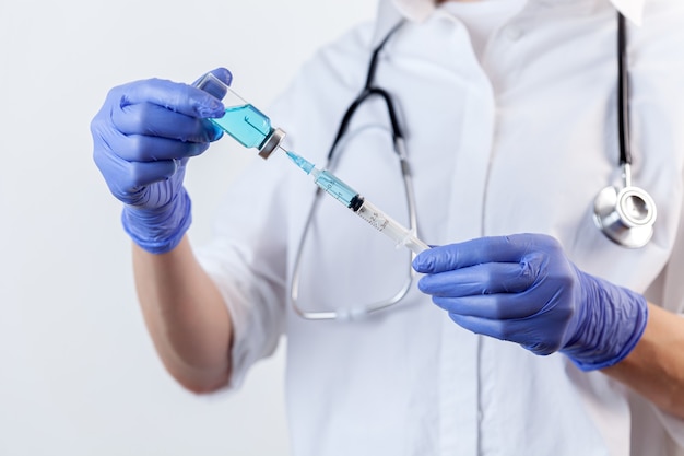 Photo closeup nurse hand in gloves holds and fills syringe from bottle with vaccine