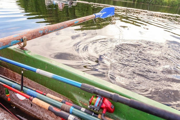 Closeup of oar paddle from row boat moving in water on green lake with ripples. Camping tourism relax trip active lifestyle adventure concept