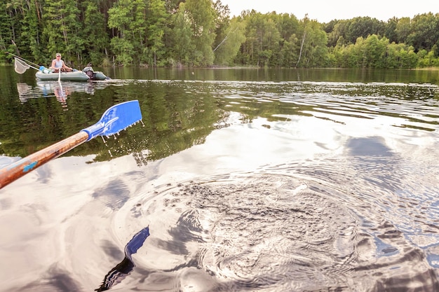 Closeup of oar paddle from row boat moving in water on green\
lake with ripples. camping tourism relax trip active lifestyle\
adventure concept