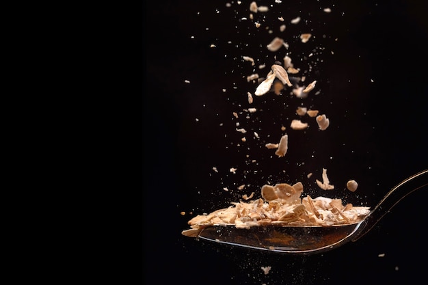 Closeup oat flakes cereals flying falling into a spoon isolated 