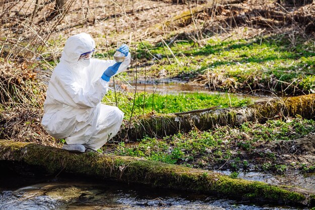 写真 森林生態学と環境汚染の概念でフラスコの液体の内容を調べる女性科学者のクローズアップ