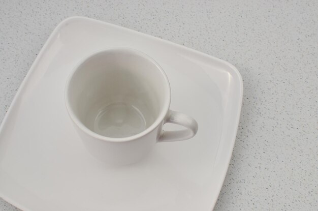 사진 백색 접시 위에 있는 고품질의 도자기 컵의 클로즈업, 채울 준비가 되어 있습니다.