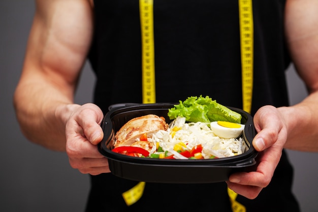スポーツ栄養のためのタンパク質が豊富な食品の完全な箱を抱えて男のクローズアップ