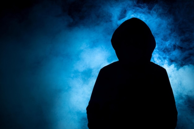 Фото Крупный план человека в темно-черном топе с синим дымом на фоне киберпреступных концепций