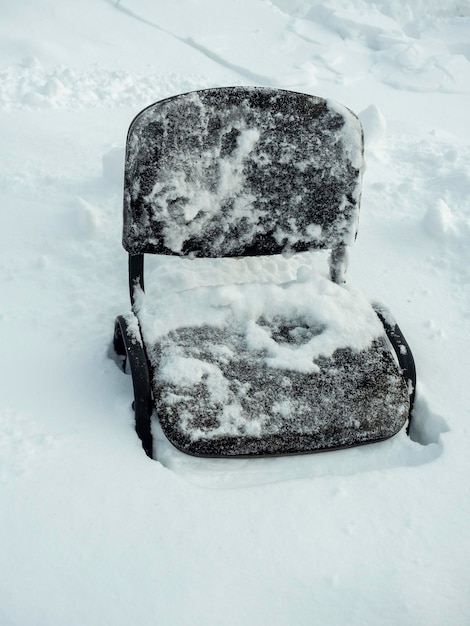 写真 冬の雪の中に立っている古い黒い椅子のクローズアップ