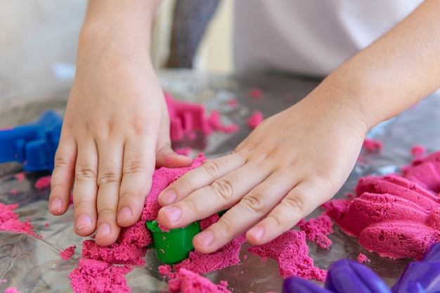 Фото Крупным планом руки ребенка, играющие в кинетическом песке