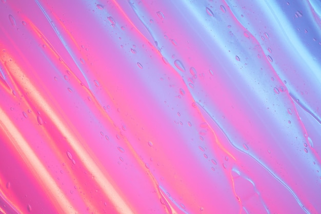 Фото Близкий взгляд на прозрачную косметическую гелевую текстуру с воздушными пузырьками внутри в красочном неоновом свете