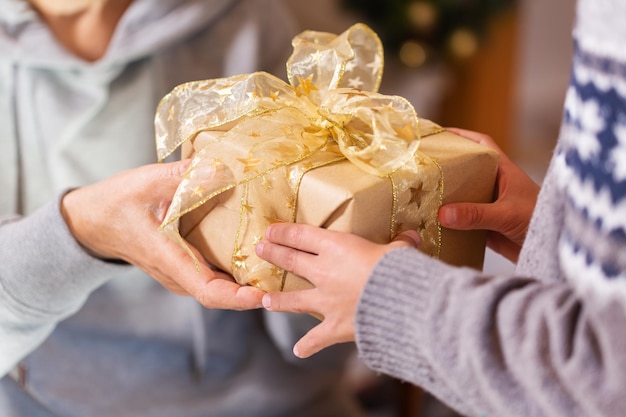 写真 クリスマスのプレゼントを握っている上級女性と子供の手のクローズアップ