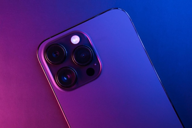 Фото Крупный план iphone 14 pro max space black, изолированный на черном фоне, освещенный синим и розовым светом слабое освещение 3 основные камеры выборочный фокус