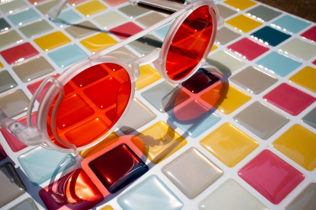 Фото Крупный снимок красных стеклянных очков на многоцветной мозаике в солнечный день