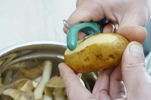 写真 ピーラー ナイフでジャガイモの皮むきを身に着けている認識できない男のクローズ アップ