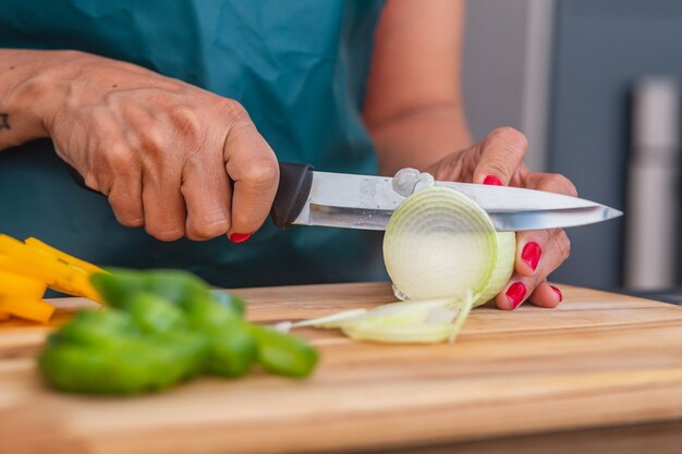 写真 ナイフとタマネギを切る女性のクローズアップ。タマネギと野菜を切るクローズアップ。