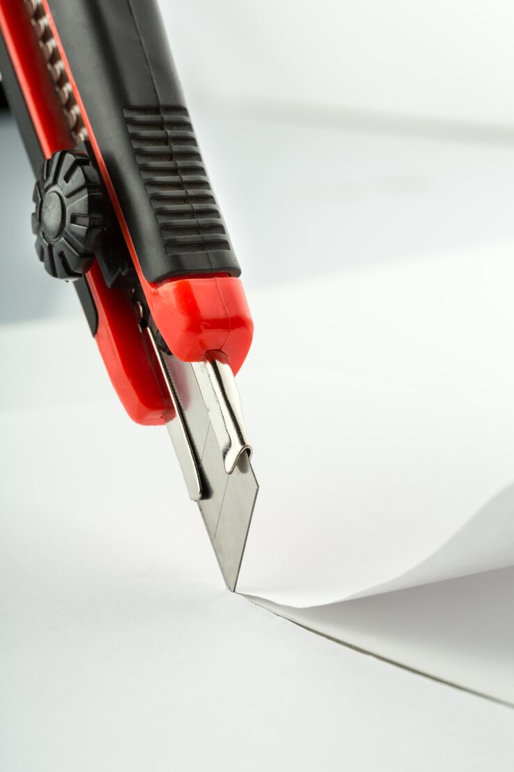 Photo closeup of office knife cutting paper