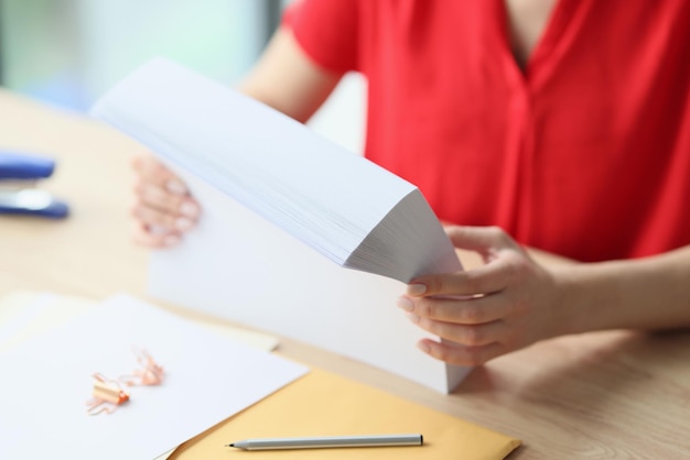 Closeup of office manager holding stack of blank paper while sitting at desk concept of