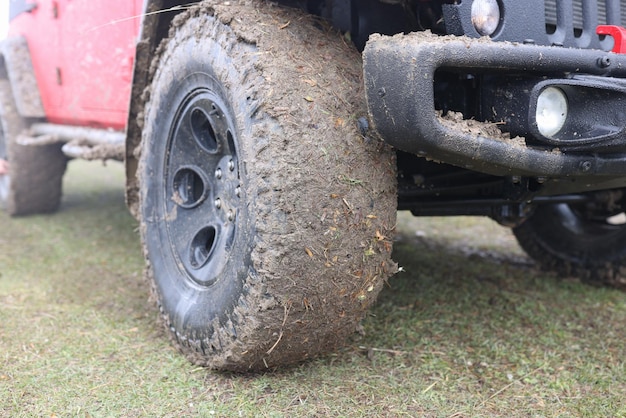 Closeup of offroad car dirty wheel suv covered with mud on countryside road adventures and