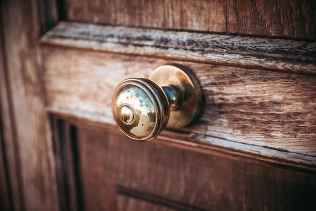 Closeup of an old corroded metal doorknob on a dark wooden door