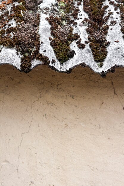 Closeup of old slate mossy roof over a clay wall