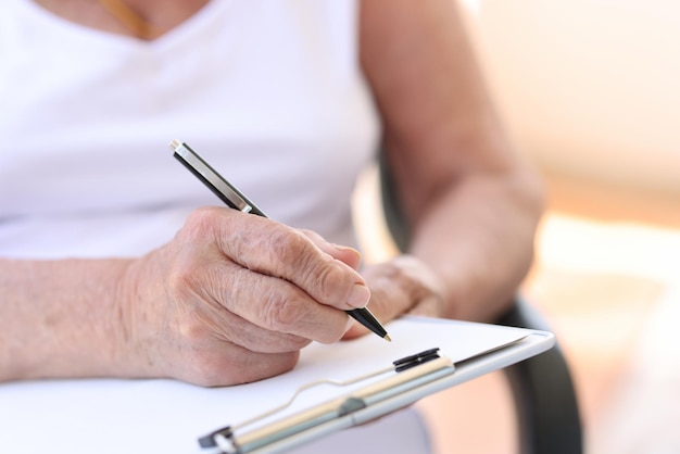 Closeup of old woman filling form in clinic or in hospice healthcare and medicine old age and