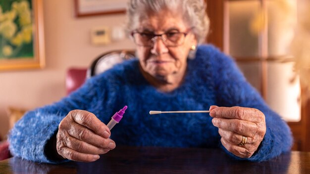 Closeup of old woman taking a self swabbing home tests Covid19 with antigen kit