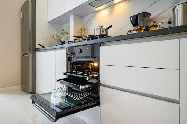 Closeup to open oven door at white modern classic kitchen