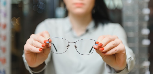 Closeup of optometrist, optician giving glasses to try