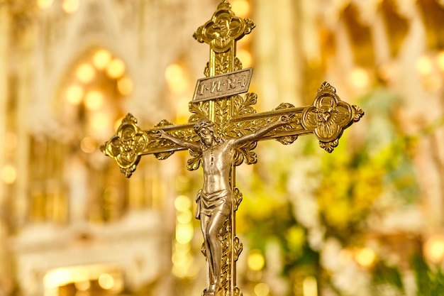 Closeup of an ornately decorated crucifix with the back wall of the sanctuary in the background