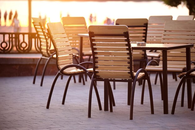 Closeup of outdoors cafe chairs and table at sunset on city street