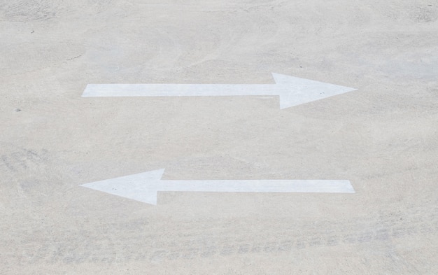 Photo closeup pale arrow sign on cement floor in the car park