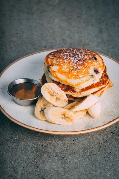 Closeup of pancakes with chocolate and bananas served on a white plate