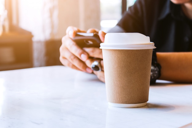 Крупным планом бумажный стаканчик горячего кофе в кафе