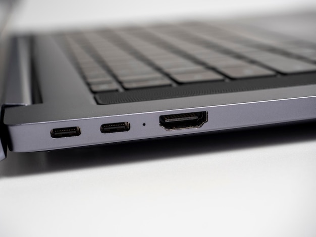 Closeup of a part of a laptop standing on a light background Large USB type S and HDMI ports on the laptop Open laptop keyboard selective focus